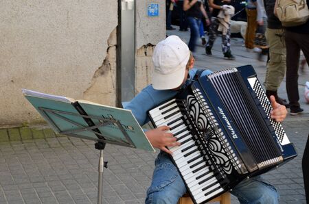 VILNIUS, LITHUANIA MAY 2012. Young child with cap plays ancient accordion. Street Musician Day. のeditorial素材