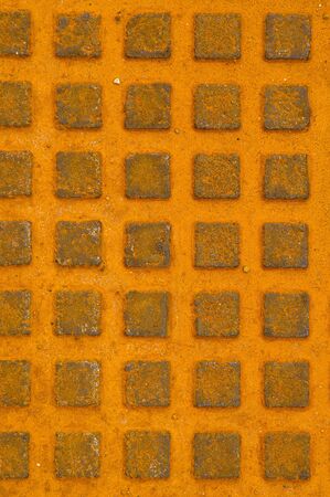 Great rusty iron metal sewer lid background. Yellow rusty steel details.の写真素材