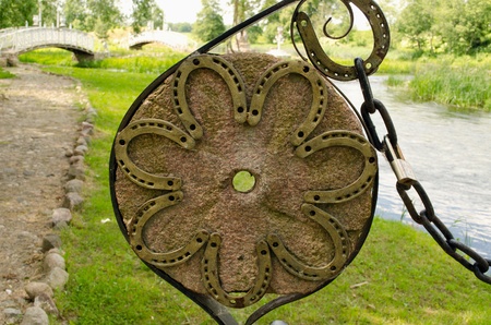Horse shoes on old millstone and chain in park and nice white bridges in distance   