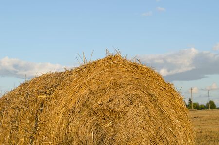 Closeup of straw bales on background of blue cloudy sky in autumn の写真素材