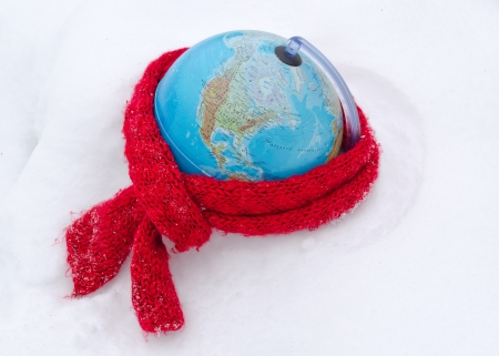 red scarf on earth globe sphere in winter snow snowbank  care of mother earth concept  の写真素材