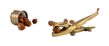 Steel crocodile nut hull shell crush tool and small cup turn out ripe cobnuts isolated on white  