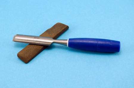 chisel graver carve tool for wood work and whetstone stone on blue background. 