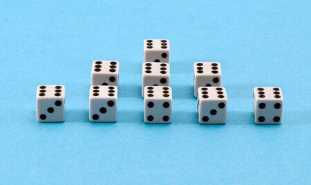 closeup of white gamble dice pyramid with six black dots on blue background  