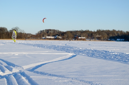 people kiteboarding and ice sailing on frozen lake in amazing cold winter day   modern recreation hobby  の写真素材