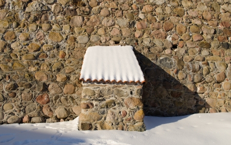 Vintage fort castle wall made of stone and small clay tile roof covered with snow in winter. の写真素材