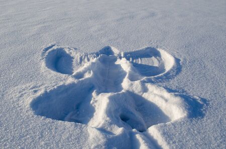 Angel silhouette on snow made by human. People make art in winter. の写真素材