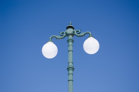 vintage lighting pole with double twin round glass lamps on background of blue sky. の写真素材