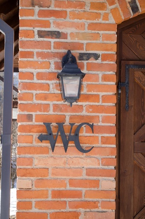 wc toilet sign symbol on red brick wall near retro lighting lamp. の写真素材