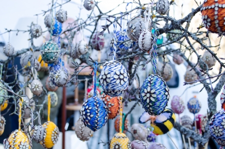 handmade easter eggs imitation decorations hang on tree branches sold in outdoor spring market fair. の写真素材