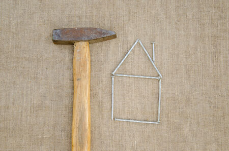 rusty hammer and shape of house made of nail, building new home concept の写真素材