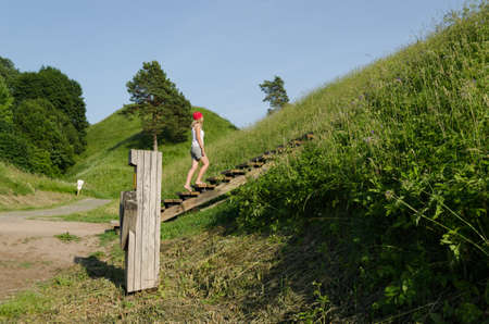 Young tourist girl climb on mound hills in Lithuanian historic capital Kernaveの写真素材