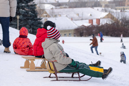 children sit on wooden sledge prepared slide from high mountain の写真素材