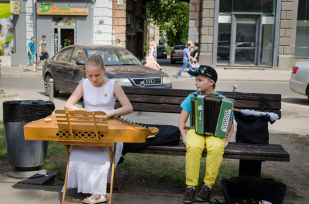VILNIUS, LITHUANIA - MAY 18: young street music festival participants girl with baltic psaltery and boy with accordion on the bench on May 18, 2013 in Vilnius. のeditorial素材