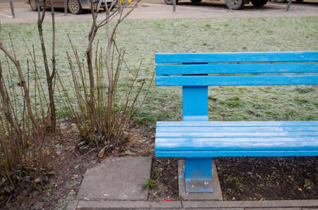blue painted wooden bench fragment near bush in the park in winter time の写真素材