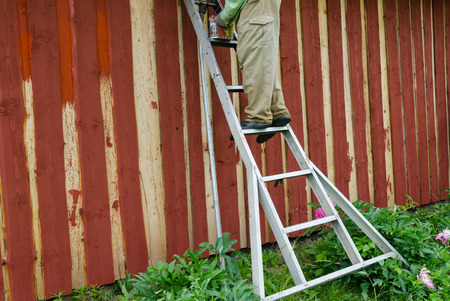 housepainter man on ladder paint wooden rural garden house wall with brush paintbrush. の写真素材