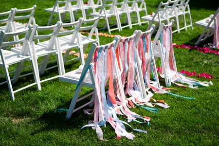 white chairs for a wedding ceremony on a green meadow with colorful stripesの写真素材