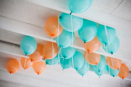 orange and green balloons with white ribbons on the ceilingの写真素材