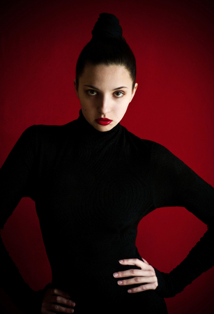 portrait of a young white girl dressed in black on a red backgroundの写真素材