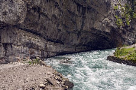 rapid mountain river in Abkhazia in the spring morning, the current from left to right, in the middle lies a log on the shore of the Bush and rockの写真素材