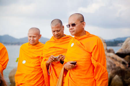 Koh Samui, Thailand - December 17 : three adult monk tourist wearing glasses and a orange dress with a camera and a phone in Thailand on Koh Samui in the feast of St. Anthony on December 17, 2012.のeditorial素材