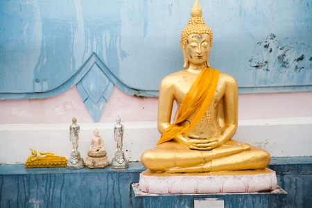 Golden Buddha with yellow fabric and little pieces close against the wall of the temple in Thailand on Koh Samuiの写真素材