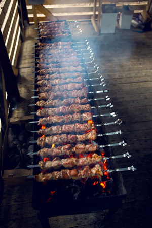 large number of preparing kebabs on the grill with coals and smoke under a canopyの写真素材