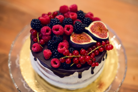 chocolate cake on stand on top sprinkled berries, figs, raspberries, red currant, BlackBerryの写真素材