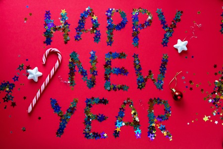 inscription colored stars new year on a red background with a large festive candyの写真素材