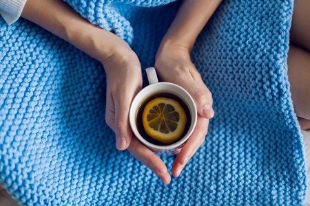 pregnant woman sitting in a white bed in a white t-shirt and drinking tea with lemonの写真素材