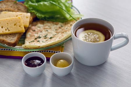 Breakfast with scrambled eggs on a transparent plate with toast, lettuce, tea with lemon , honey and raspberry jamの写真素材