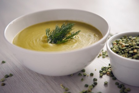 pea soup on a wooden table with an iron spoonの写真素材