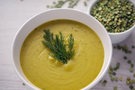 pea soup on a wooden table with an iron spoonの写真素材