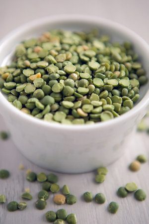 green peas in a white saucer on a white tableの写真素材