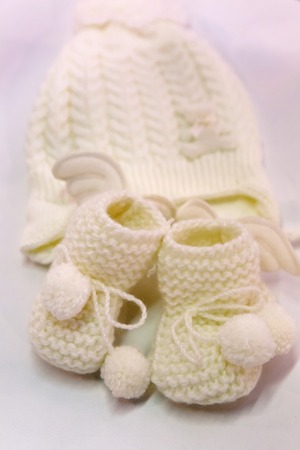 white knitted baby booties and hat on a light background