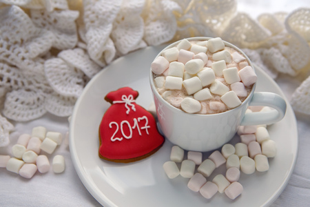 white Cup of cocoa on a saucer, marshmallows and a candy stand on the sill of the window