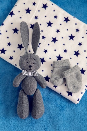 gray toy rabbit lies next to a gray socksの写真素材