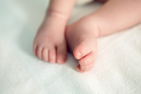 two feet of a newborn lying on white sheetsの写真素材