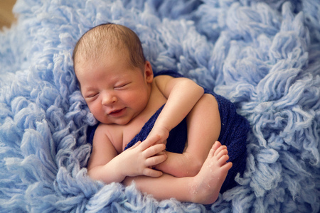 Newborn boy lies on a bed in blue fur and sleeps sweetlyの写真素材