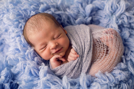 Newborn boy lies on a bed in blue furの写真素材