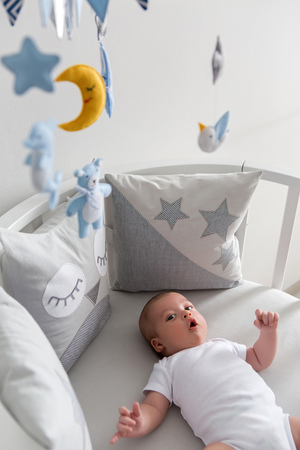 newborn lies in the round white bed with mobile