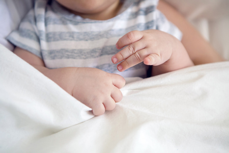 hand baby lying in bed and coveredの写真素材