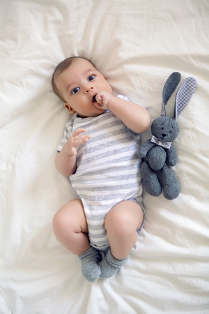 the child lies on his back on a big white bedの写真素材