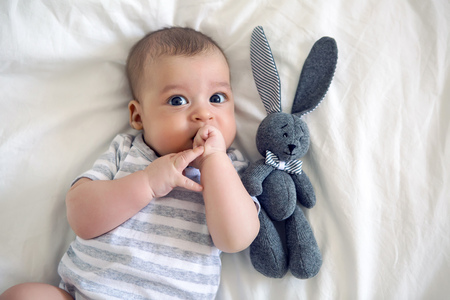 the child lies on his back on a big white bedの写真素材