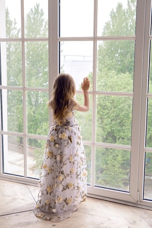 baby girl in a long floral dress standsの写真素材