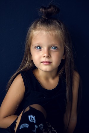 baby girl with long hair in leather jacket standing in the studioの写真素材