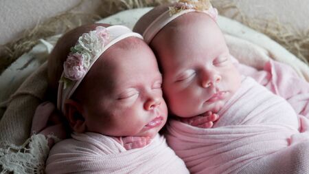 twin babies sleep in the crib in dresses and headbandの写真素材