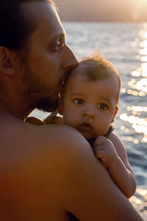 father with a young son on beach with sunset