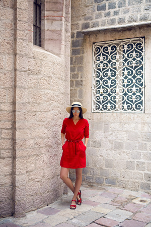girl in red dress standing at stone wall of the castle in Montenegroの写真素材
