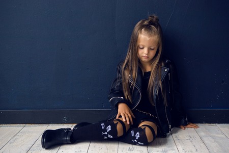 sad girl in a leather jacket rock home sitting on white floorの写真素材